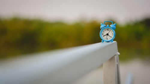 Close-up of clock on railing against blurred background