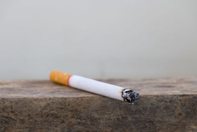 Close-up of lit cigarette on wooden retaining wall