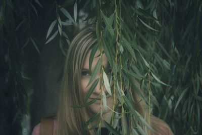 Headshot of young woman behind leaves