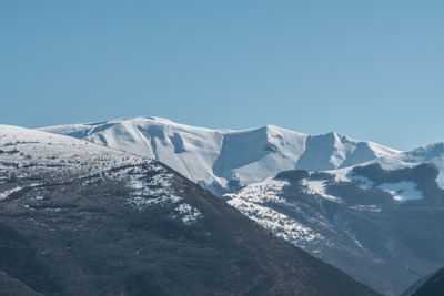 Scenic view of snowcapped mountains against clear blue sky