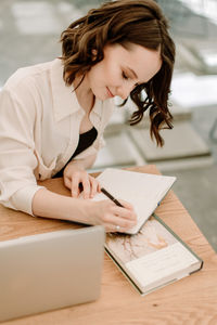 Young woman looking away while sitting on table