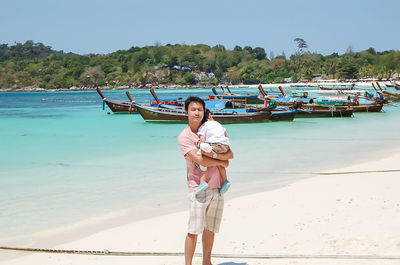 Portrait of father carrying son while standing at beach