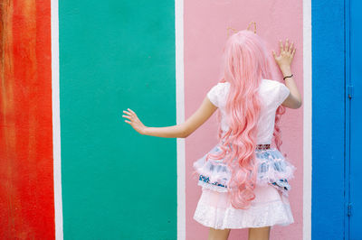 Rear view of woman standing against colored wall