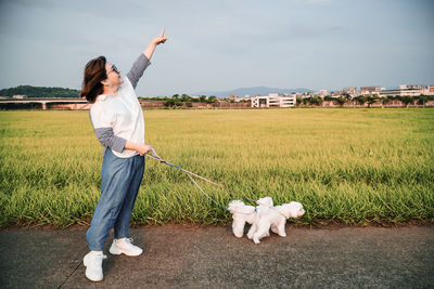 Full length of woman standing with dogs by land