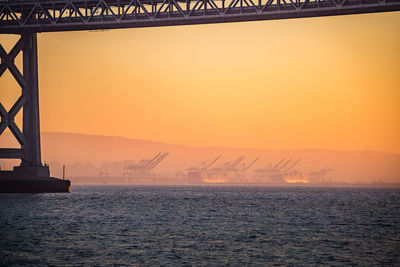 Cranes at harbor against sky