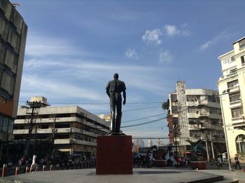 Statues on street amidst buildings in city against sky