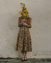  woman standing against wall with mimosa flowers