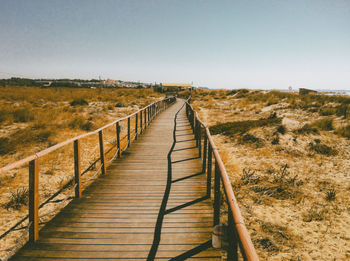 Boardwalk on landscape against clear sky