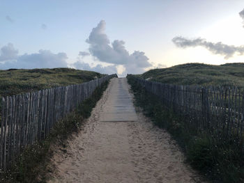 Footpath amidst field against sky