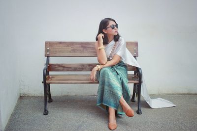 Full length of young woman sitting on bench