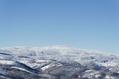 Aerial view of snowcapped mountain against clear blue sky