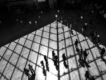 High angle view of people walking on floor with shadow of ceiling