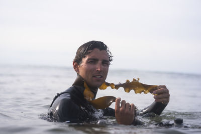 Young man having fun playing with seaweed