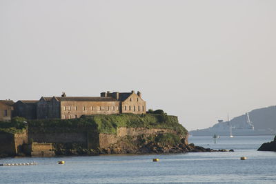 Buildings by sea against clear sky