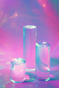 Three clear glass cylinder podiums on pastel pink background