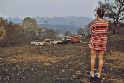 Rear view of woman standing on field against sky