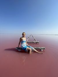 Woman sitting against clear blue sky rose water
