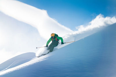 Man skiing on snowcapped mountain against sky