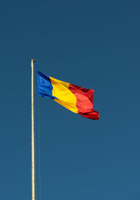 Low angle view of flag against blue sky