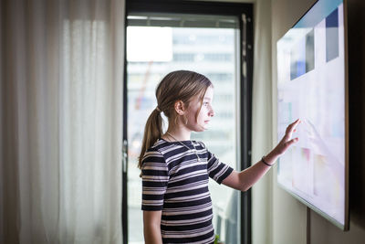 Girl touching digital screen of smart tv at modern home