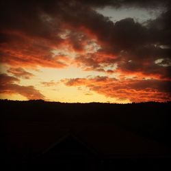 Silhouette landscape against dramatic sky during sunset