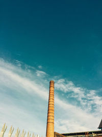 Low angle view of smoke stack against blue sky