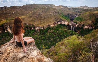 Woman sitting on rock looking at mountains