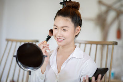 Smiling woman applying make-up at home