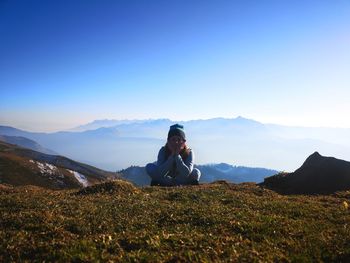Sitting on mountain against sky