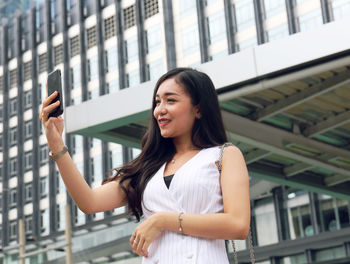 Portrait of young woman standing on mobile phone