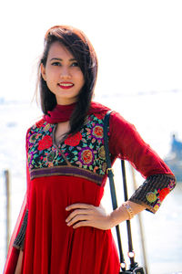 Portrait of smiling young woman standing against sky