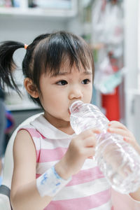 Close-up of cute girl drinking water while sitting on chair at restaurant