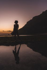 Silhouette man standing on shore against sky during sunset