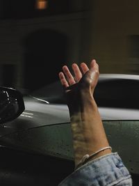 Cropped hand at car window during rain