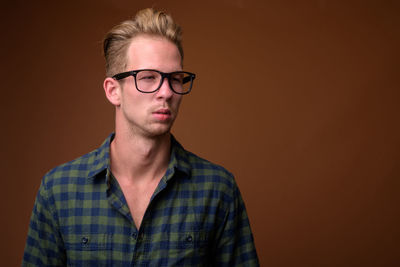 Portrait of young man wearing eyeglasses against black background