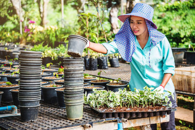 Woman standing by potted plants in yard