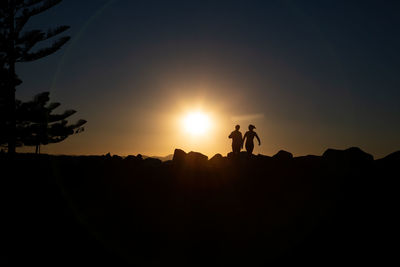 Silhouette people standing against sky during sunset