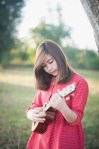 Young woman playing guitar in park