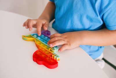 Little boy plays with rainbow pop it fidget toy. antistress children game. trendy silicone toy