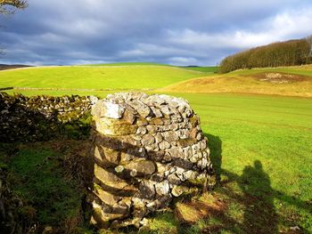 Stone wall on field against sky