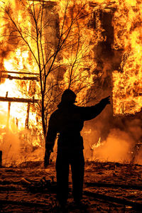 Firefighter standing by burning fire at night