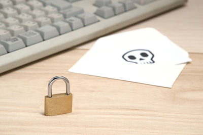 Close-up of padlock by envelope and computer keyboard on table