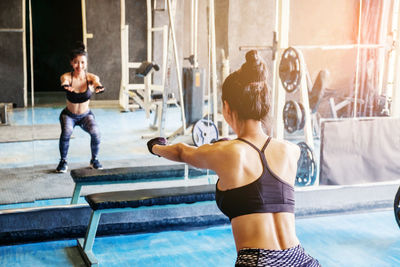 Rear view of young woman exercising in gym