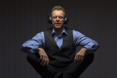 Portrait of mature man standing against black background