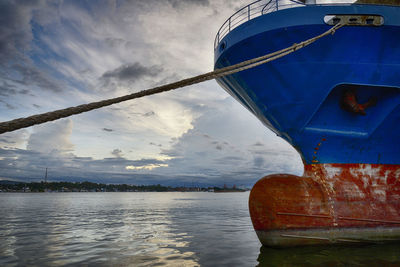 Boats in river against cloudy sky