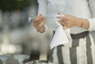 Close-up of waitress cleaning wine glass