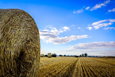 Hay bales on field against sky