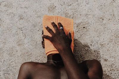 High angle view of shirtless man sitting on sand