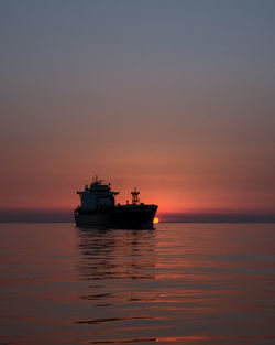 Ship sailing on sea against sky during sunset