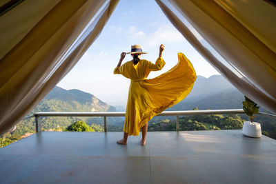 Asian female tourist in beautiful yellow dress, beautiful sky and mountains of nature, chiang rai.